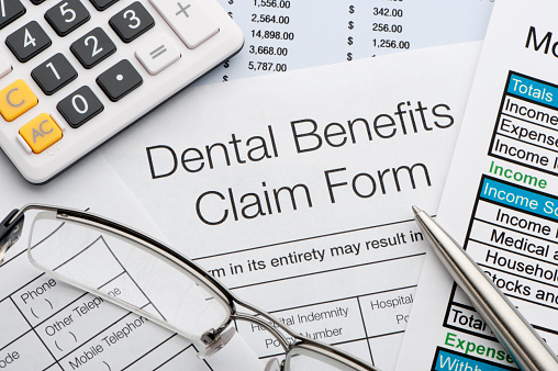 Close up a Dental benefits claim form with calculator and pen | EZDDS Dental Billing Company